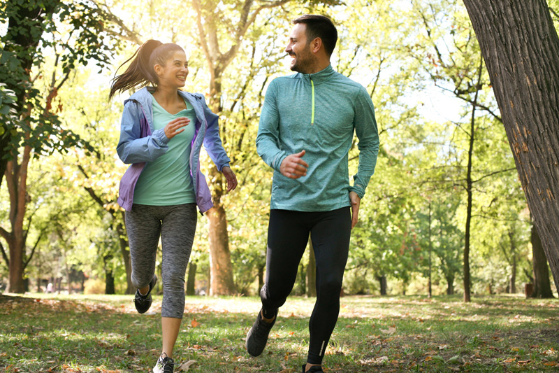 Healthy couple running in a park. Oak Enrichment Concierge Wellness.